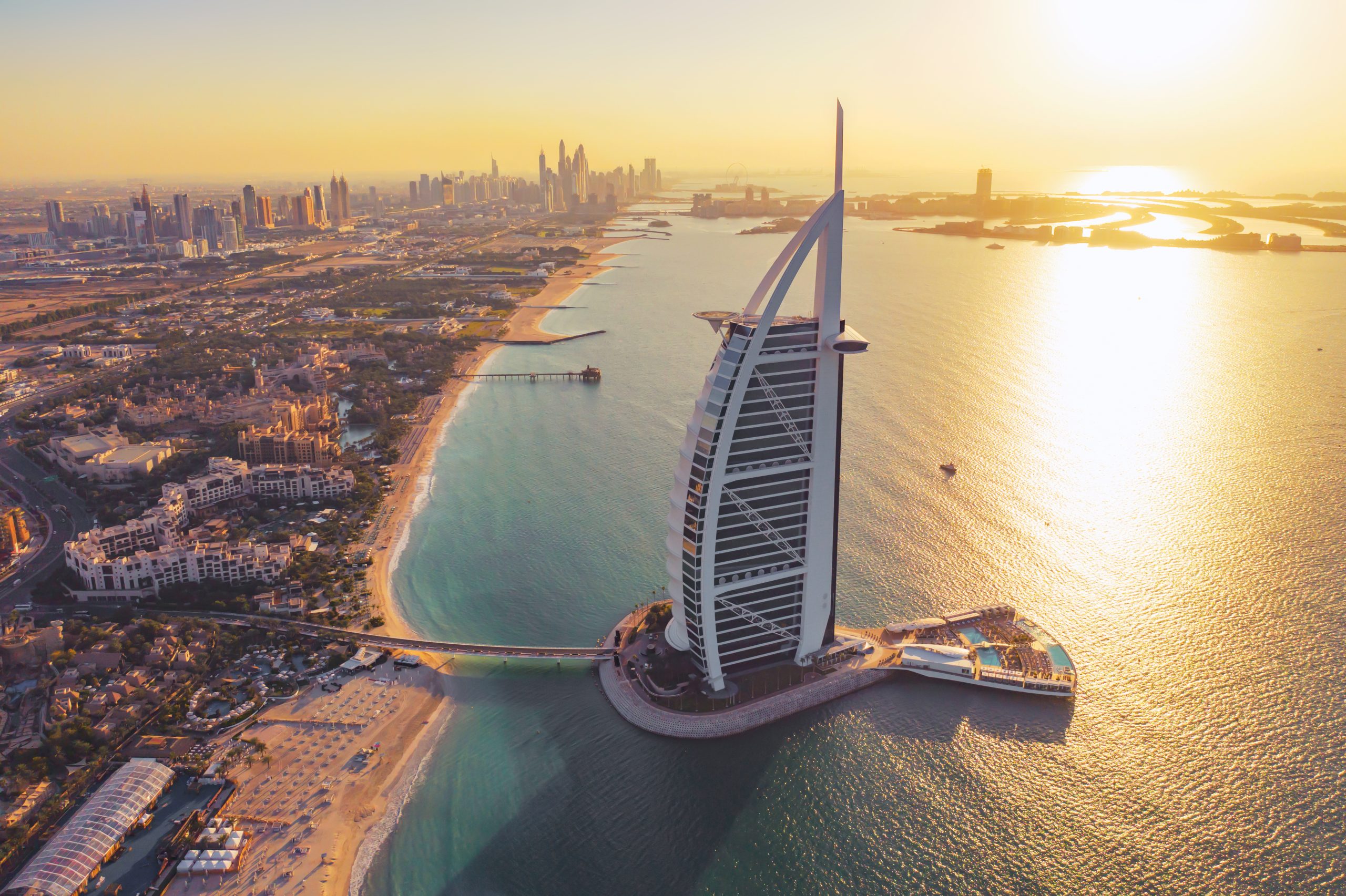 Aerial view of Burj Al Arab Jumeirah Island or boat building, Dubai Downtown skyline, United Arab Emirates or UAE. Financial district in urban city. Skyscrapers at sunset.