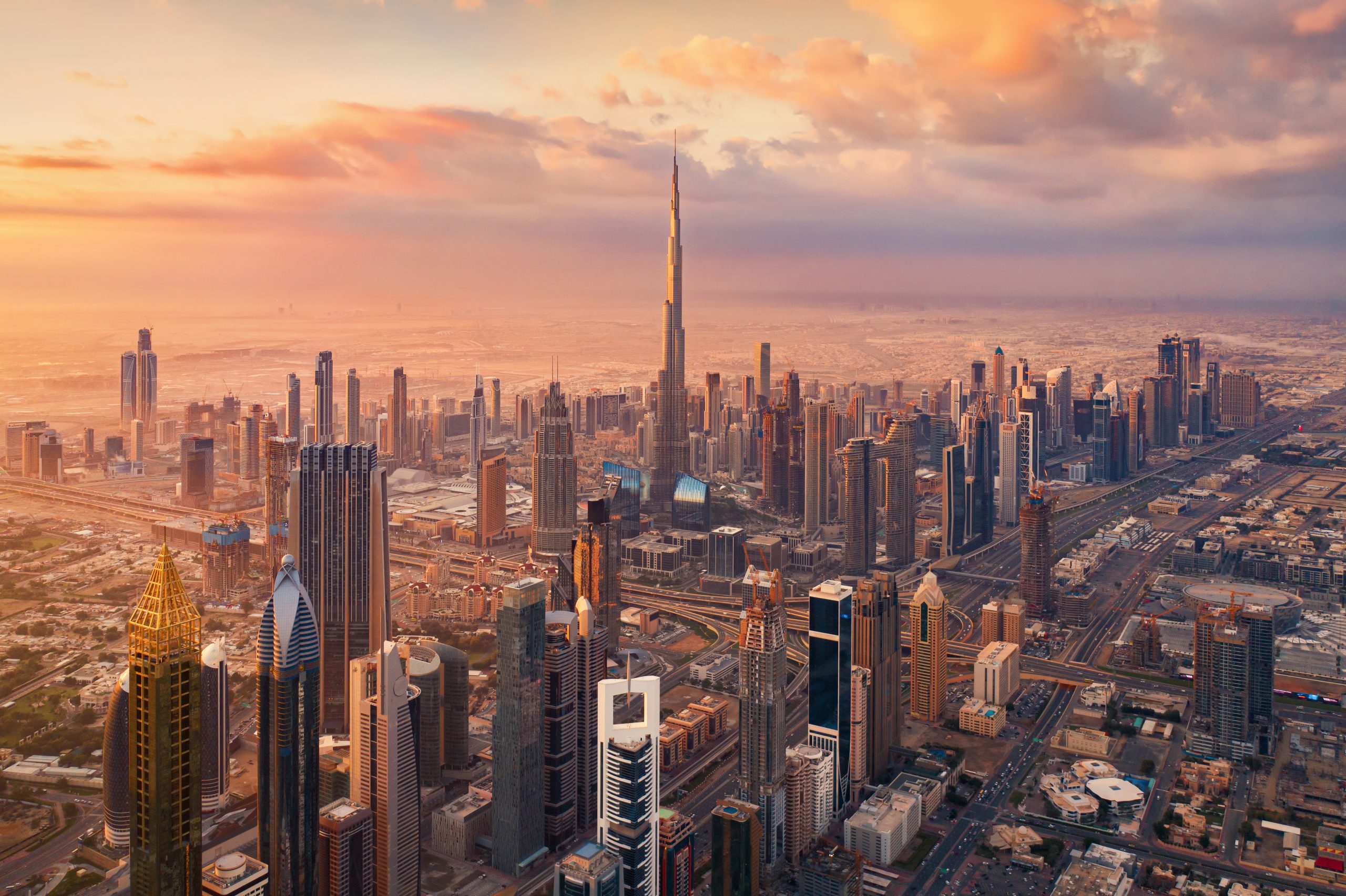 Aerial view of Burj Khalifa in Dubai Downtown skyline and highway, United Arab Emirates or UAE. Financial district and business area in smart urban city. Skyscraper and high-rise buildings at sunset.