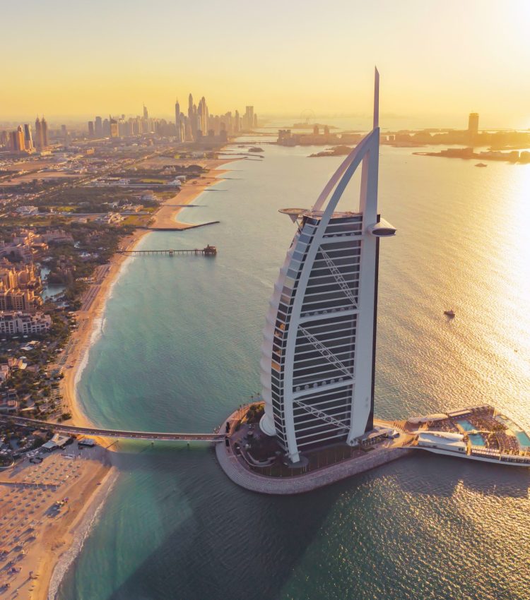 Aerial view of Burj Al Arab Jumeirah Island or boat building, Dubai Downtown skyline, United Arab Emirates or UAE. Financial district in urban city. Skyscrapers at sunset.